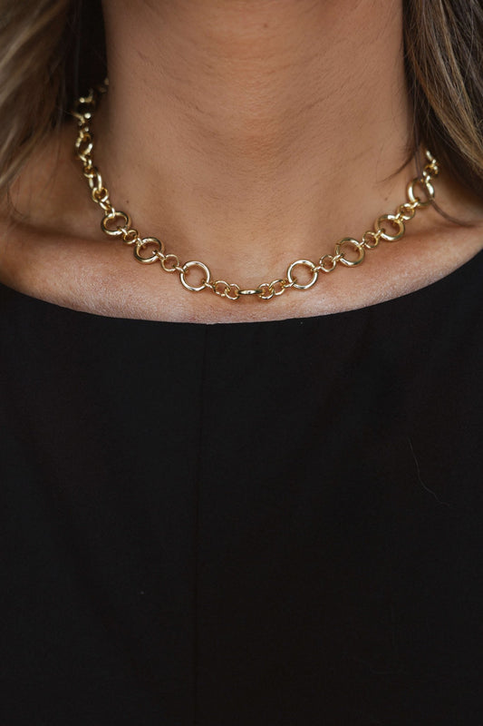 She accessorizes her black top with the Gold Dipped Circle Chain Link Necklace—an elegant holiday statement.