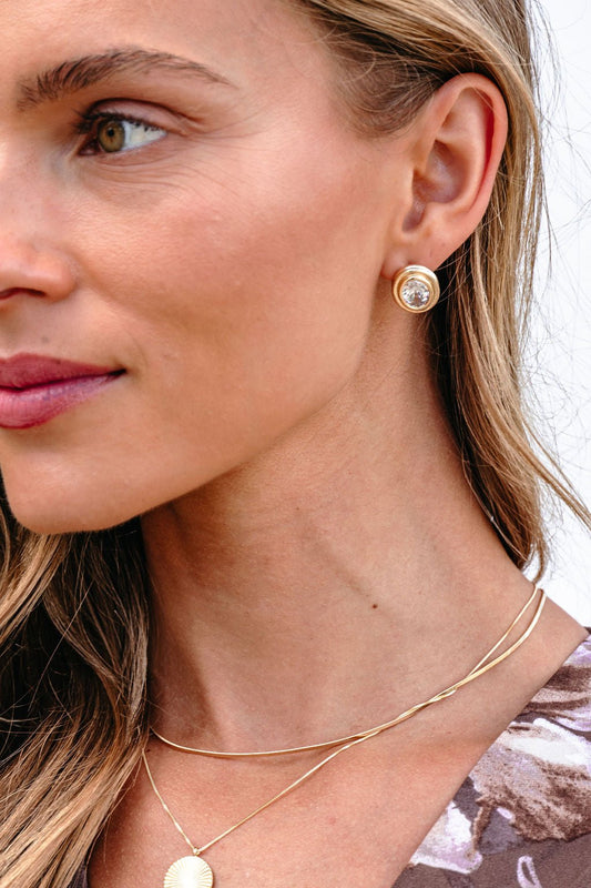 Woman with light brown hair wears Gold Dipped Oval Stud Earrings, shown from the side against a light background.
