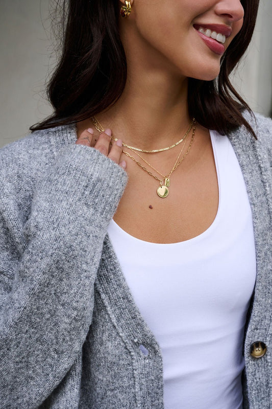 Woman smiling in a cozy gray cardigan and white top, wearing the Gold Dipped Pendant Layered Necklace.