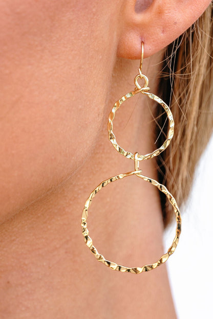 Close-up of Gold Double Hoop Dangle Earrings with a hammered texture, shown worn on ear.