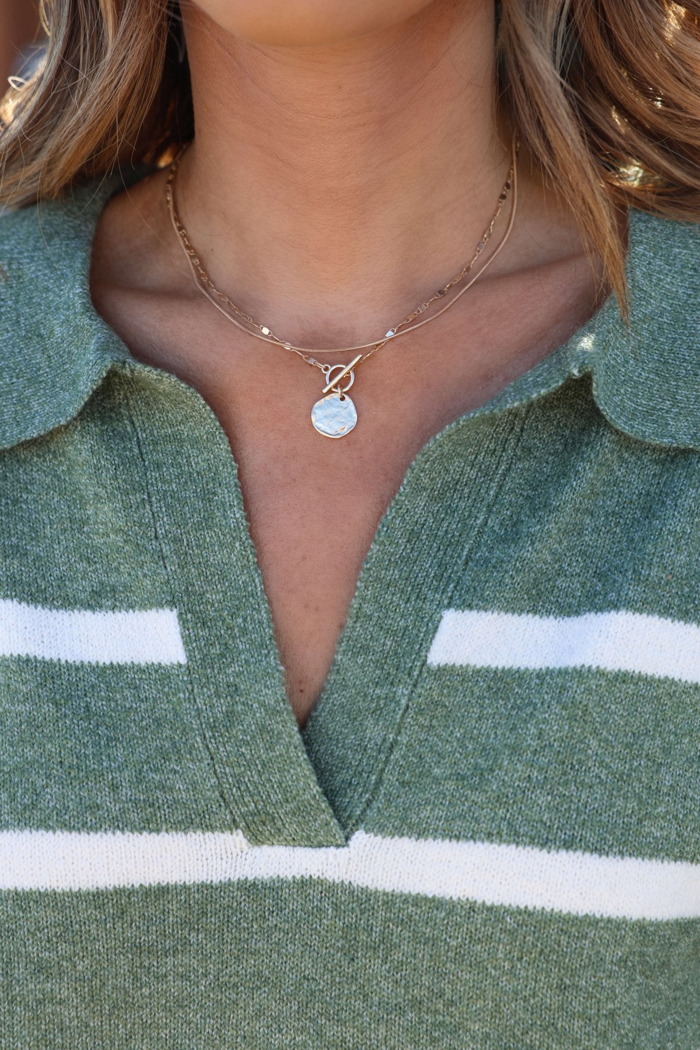 Close-up of a person in a green collared sweater, styled with the Gold Double Layer Hammered Pendant Necklace.