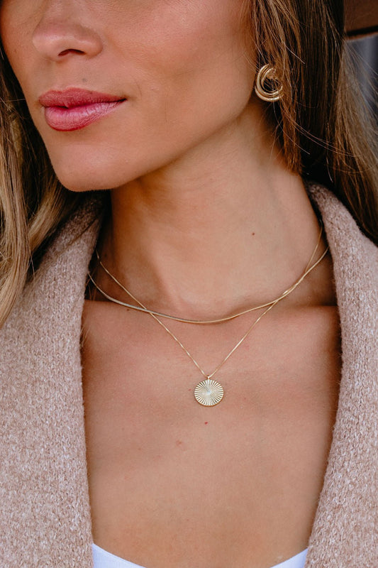 Woman in a tan coat, gold hoop earring, and Gold Layered Disc Pendant Necklace.