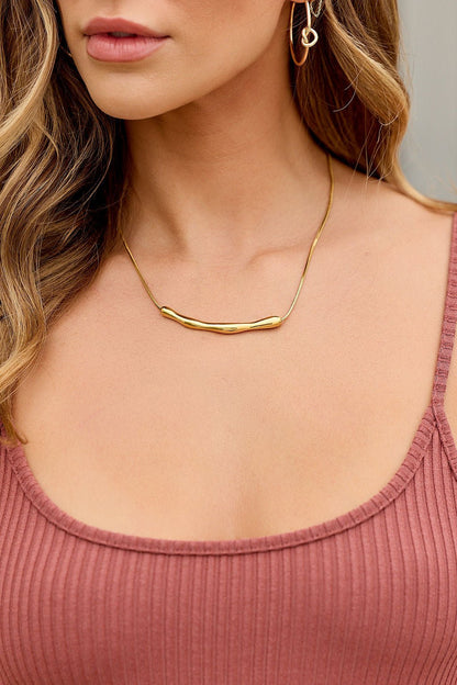 Woman wears a ribbed mauve tank, gold earrings, and the Golden Bar Pendant Necklace; only her neck and lower face are visible.