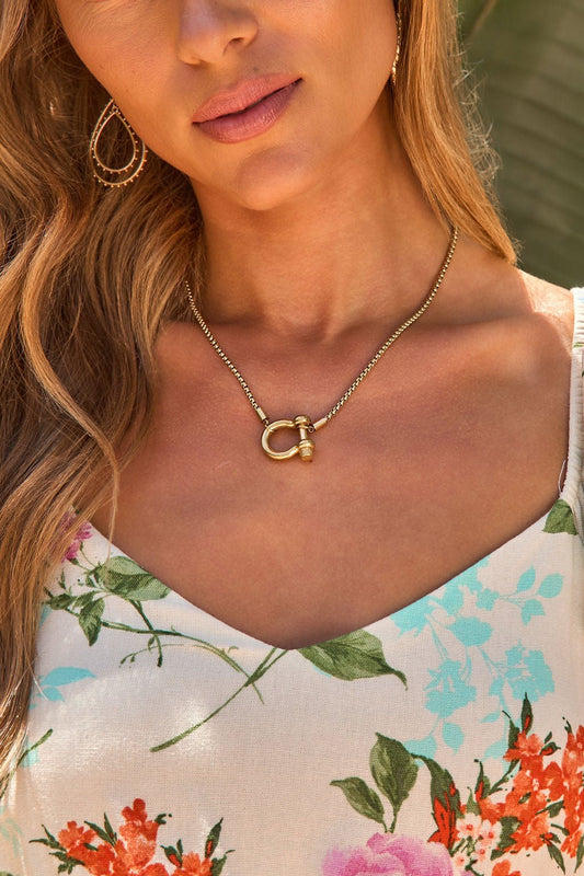Woman in a floral v-neck top styles the Golden Loop Chain Necklace—modern, versatile jewelry for any occasion.