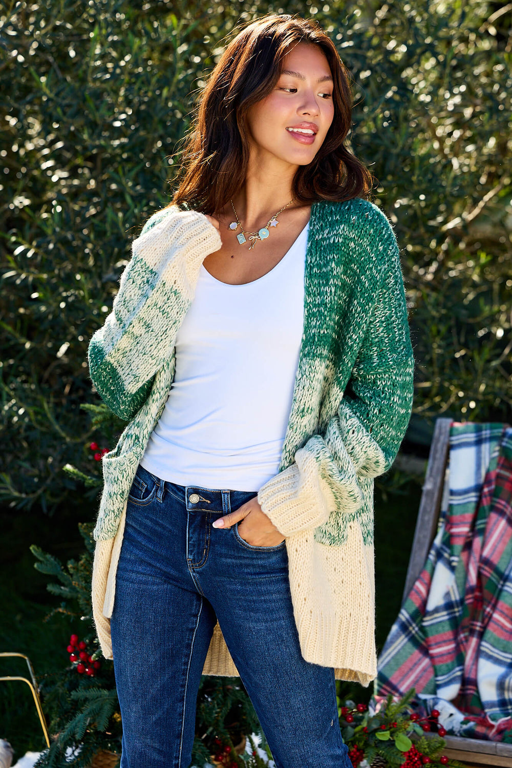 A woman smiles outdoors in the Green Ombre Open Front Cardigan - FINAL SALE, with trees and a plaid blanket in the background.