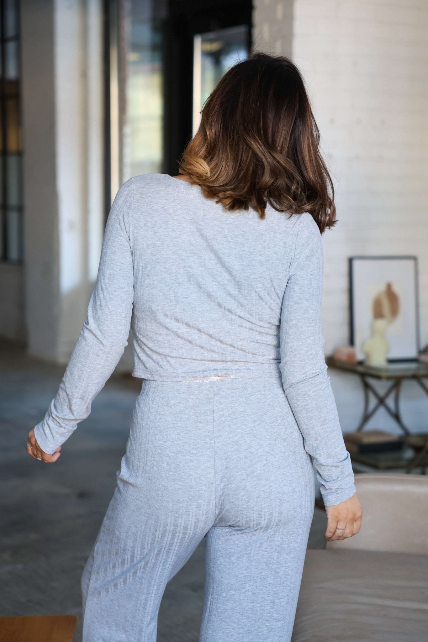 A woman stands indoors, facing away, wearing a Grey Lace Trim Lounge Set.