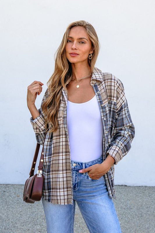 Woman with long blonde hair wears the Grey Plaid Button Down Top over a white tank top and jeans, holding a brown handbag.