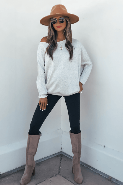 Woman wears a Grey Soft Cloud Scuba Pullover with tan hat, sunglasses, and black pants against a white wall.
