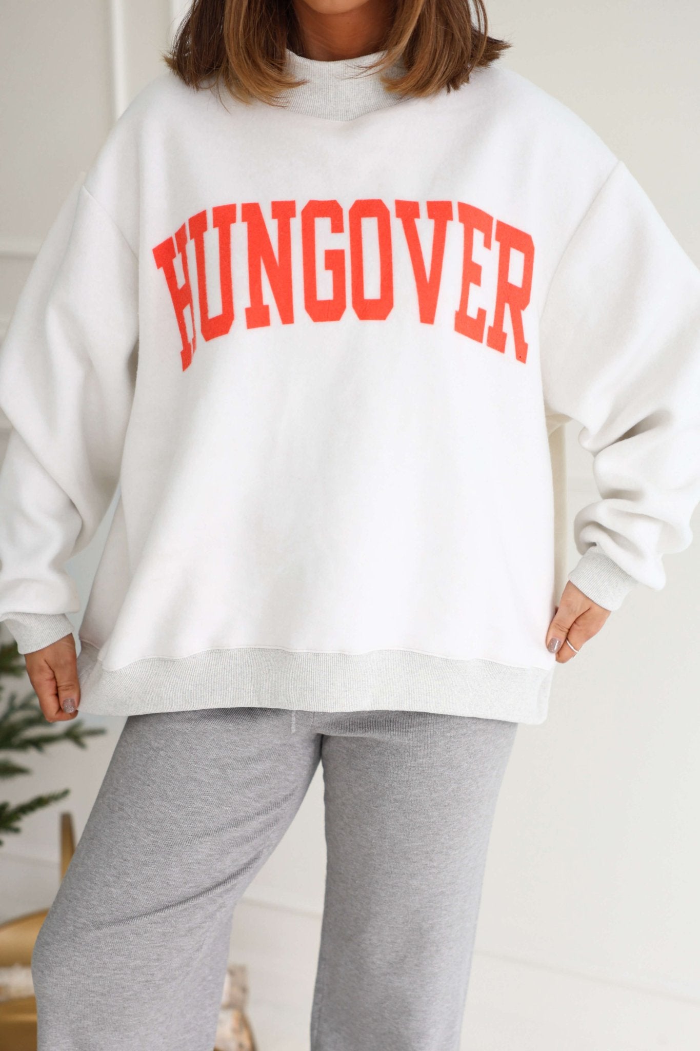 A person indoors in a cozy Grey Spicy Margs Reversible Sweatshirt and gray sweatpants.