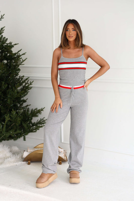 Woman in Grey Striped Drawstring Pants stands by a Christmas tree in a modern, light-colored room.