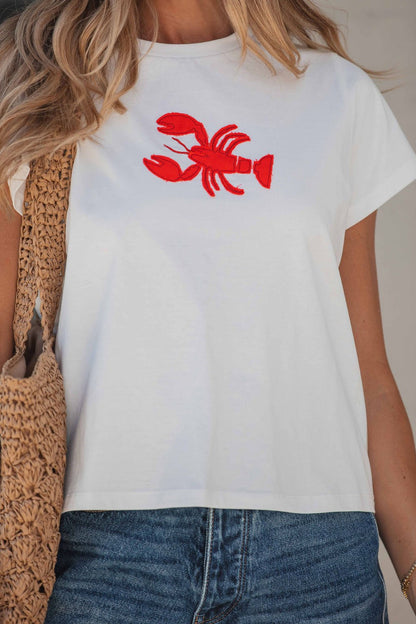 A woman in the Harbor Lobster Patch Tee, blue jeans, and a straw bag for a classic coastal vibe.