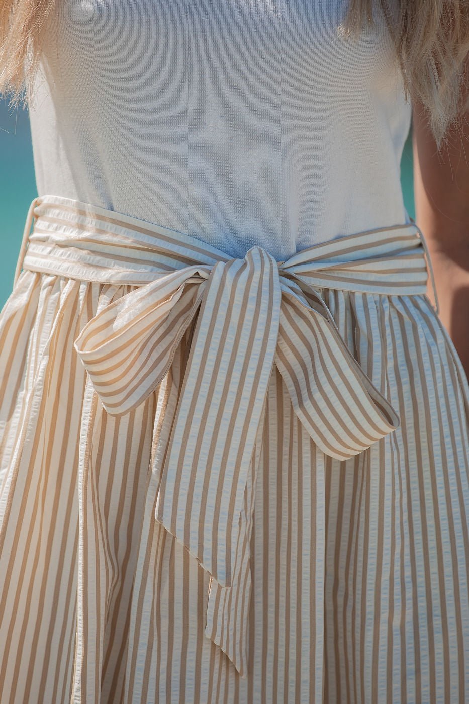 Close-up of the Harbor Stripe Tie Midi Dress - Taupe, a cotton blend midi with matching belt, styled with a white top.