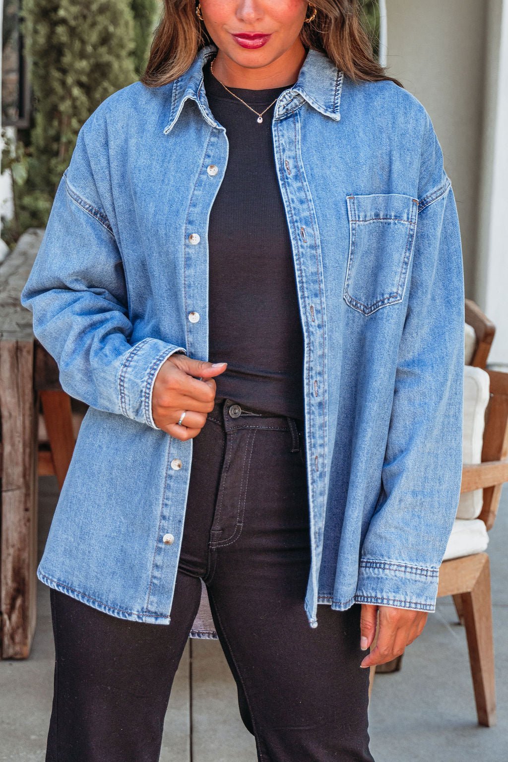 A woman wears the Harvest Blues Denim Shacket, 100% cotton, over black clothes outdoors—a perfect fall layer.
