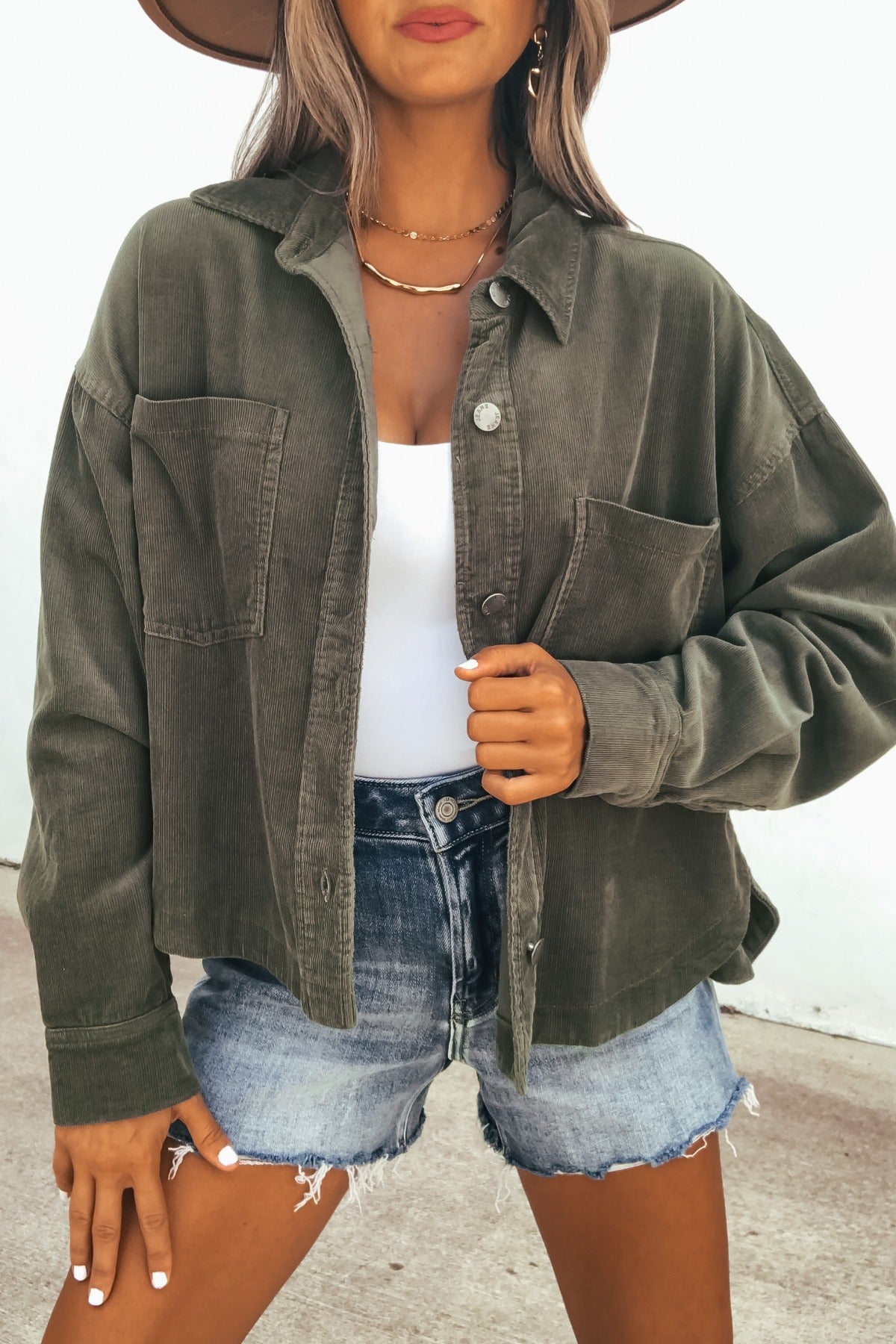 Woman in a Hunter Green Corduroy Shacket and denim shorts, outdoors—the perfect transitional layer for breezy days.
