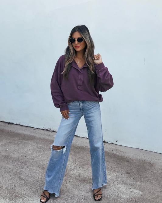Woman wearing an oversized, dark cherry Button Front Sweatshirt and light wash distressed jeans.