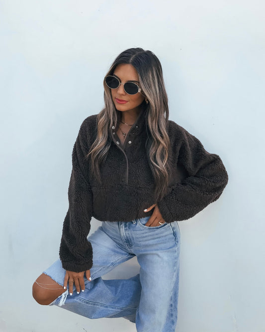 A woman wearing an oversized brown Half Zip Sherpa Jacket and light-wash distressed jeans.