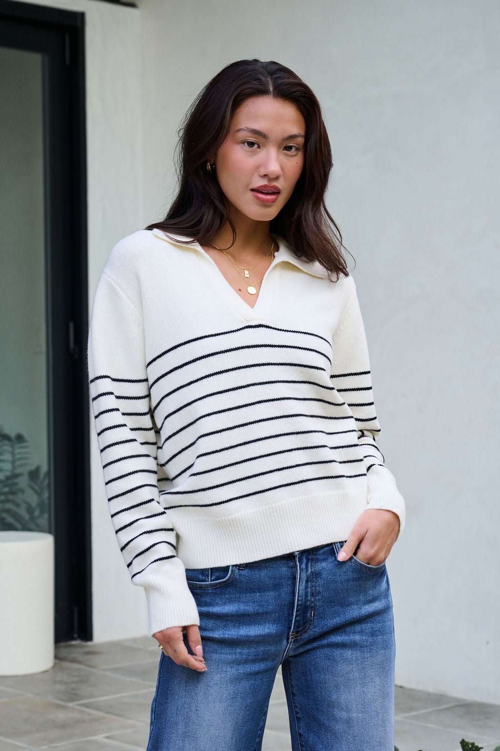 Model wearing the Ivory and Black Stripe Ribbed Sweater with blue jeans—ideal for your winter wardrobe.