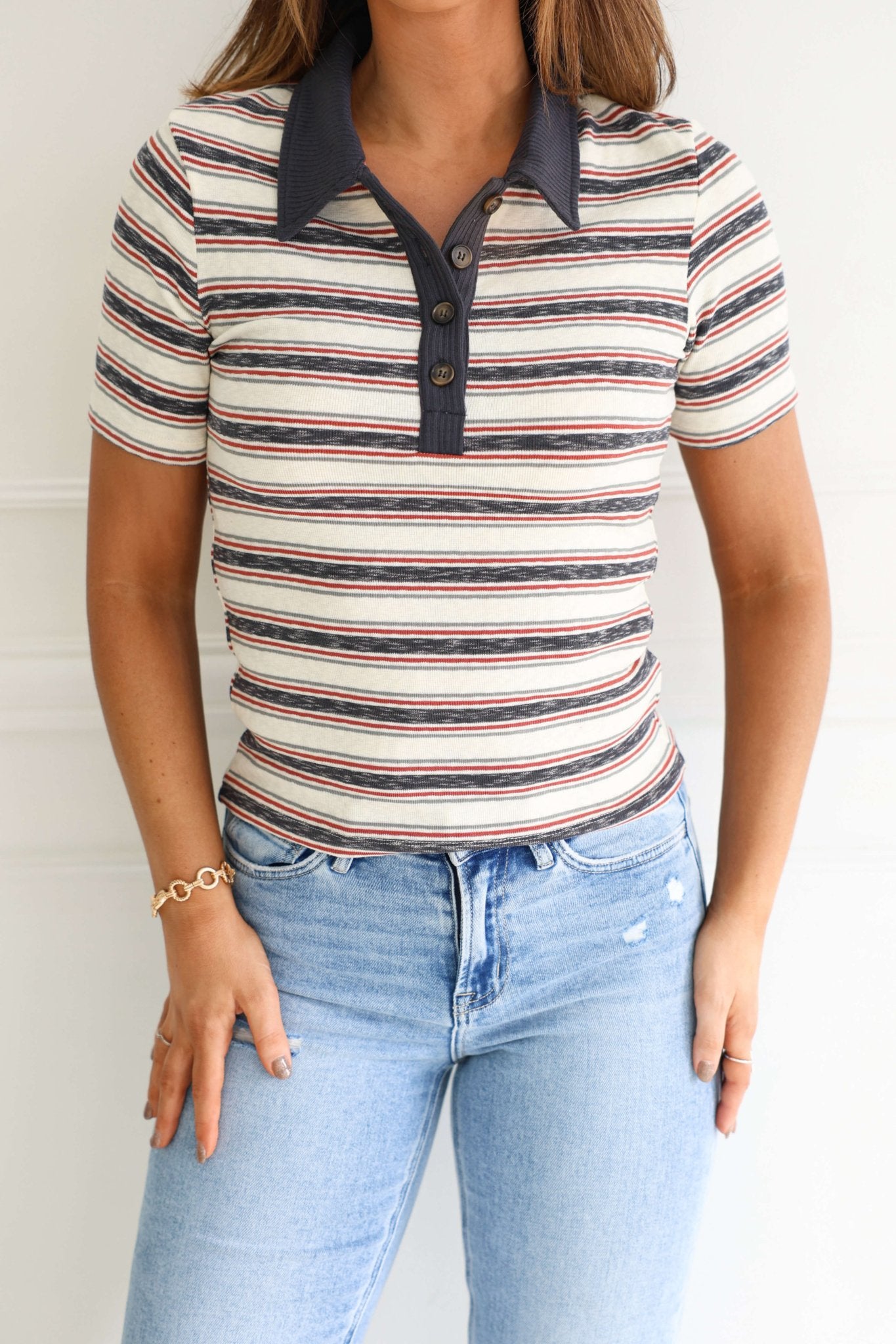 Woman in Ivory Contrast Striped Rib Polo Top and light blue jeans, standing against a white background.
