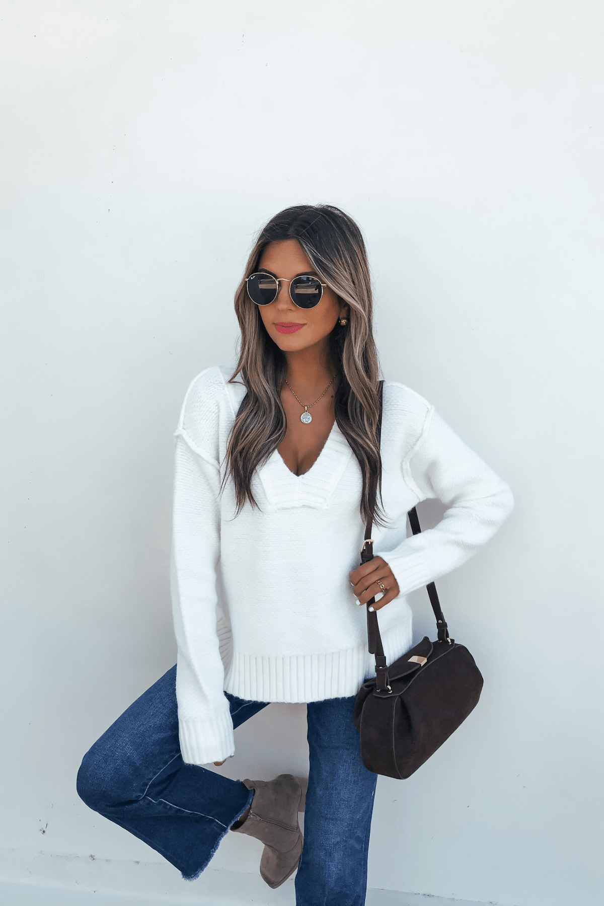 Woman wearing sunglasses, jeans, and boots holds a brown handbag, styled in the Ivory Seam Detail Ribbed Sweater, on a white background.