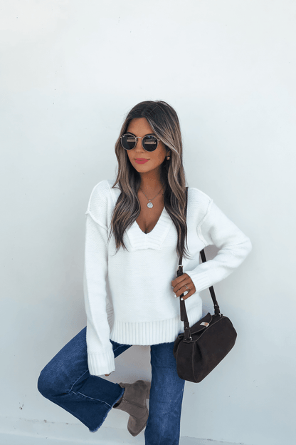Woman wearing sunglasses, jeans, and boots holds a brown handbag, styled in the Ivory Seam Detail Ribbed Sweater, on a white background.