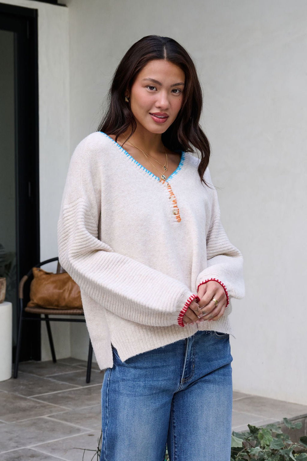 A woman in the Ivory Stitch Trim Button Up Sweater stands outside in blue jeans, smiling at the camera.
