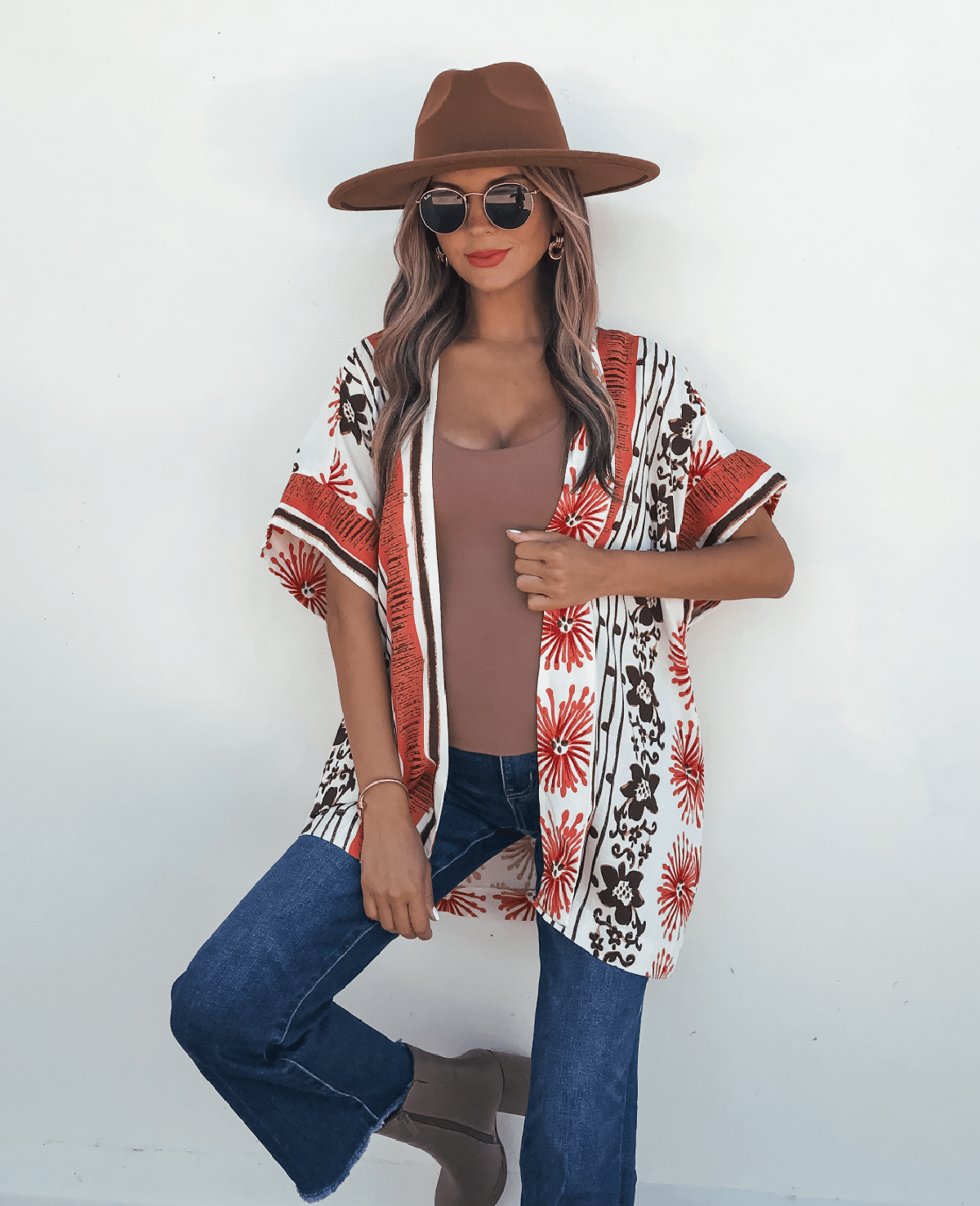 Woman in sunglasses, brown hat, blue jeans, boots, and a Jolene Multi Red Border Print Kimono Top posing against a white background.