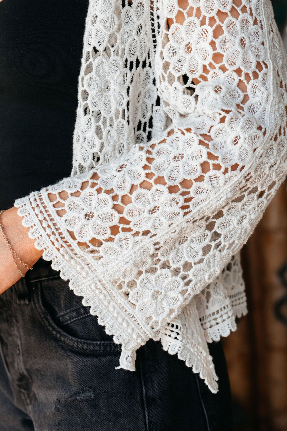 Wearing black jeans, a black top, and the Kimono Sleeve Tie Front Crochet Cardigan—an ideal lightweight summer layer.
