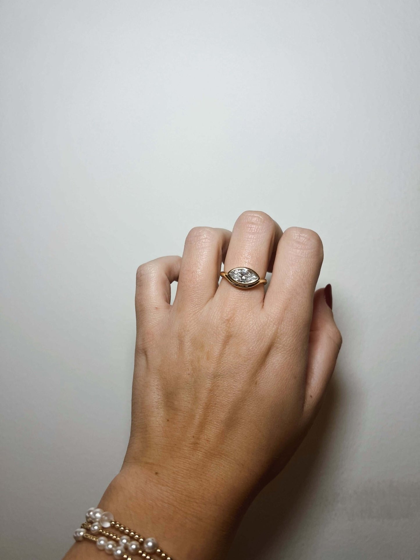 A hand wearing the Kinsey Designs Griffin Gold Solitaire Ring with a marquise-cut CZ, shown against a plain white background.