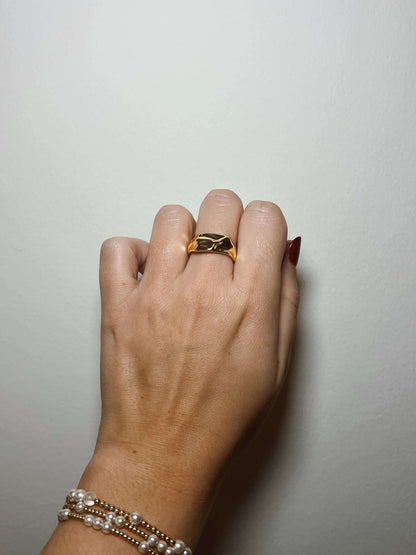A hand wears the Kinsey Designs Sybil Gold Molten Ring and pearl bracelets against a plain white background.