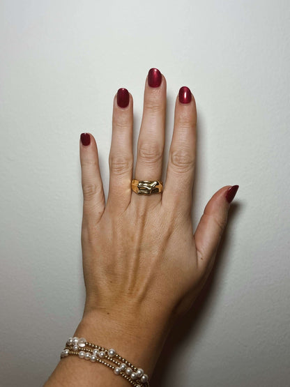 A hand with dark red nails wears the Kinsey Designs Sybil Gold Molten Ring against a plain white background.