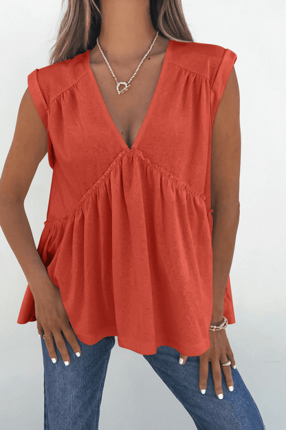 Woman in Lena's Carefree Afternoon Coral Babydoll Top and blue jeans, styled with rings and a necklace.