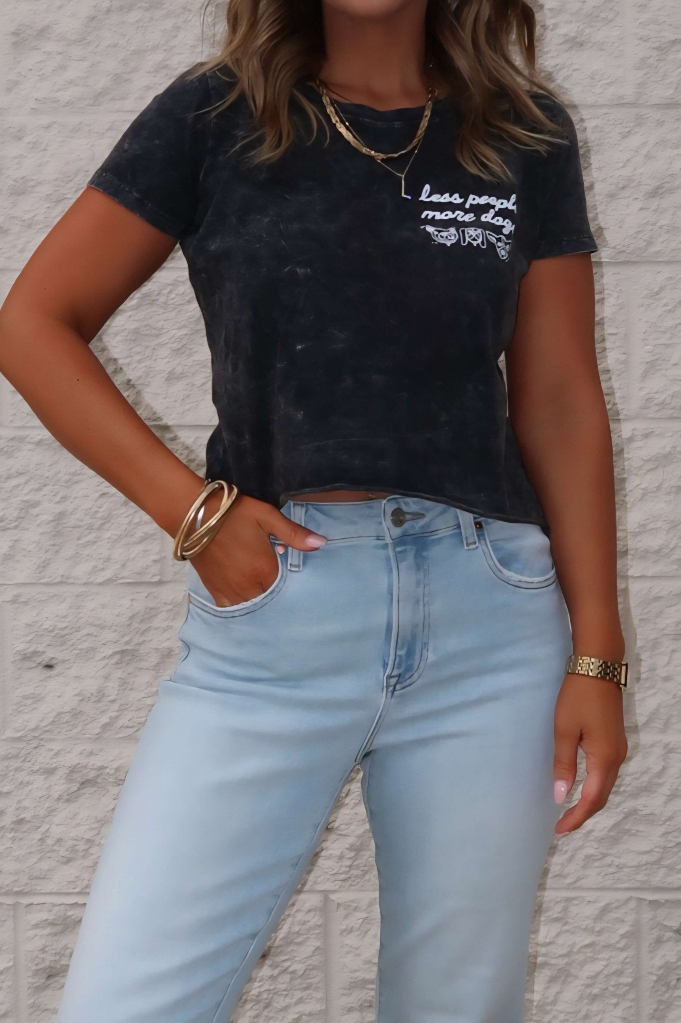 Woman wears a Less People More Dogs Graphic Tee - Black with light blue jeans and gold jewelry—perfect for dog lovers.