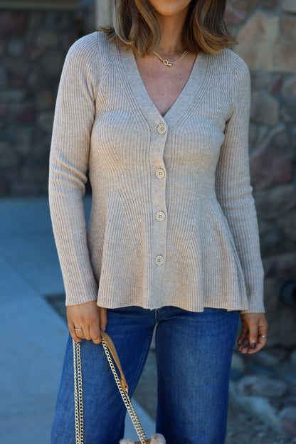 Woman in Light Tan Hourglass Sweater Cardigan with buttons, blue jeans, and a chain strap bag, standing outdoors.