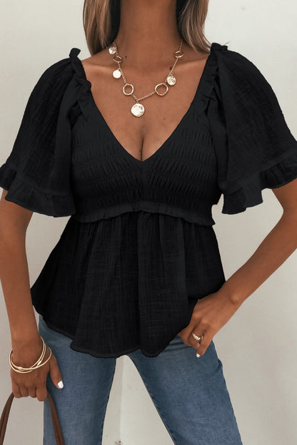 Woman in Lola Black Ruffled Babydoll Top, blue jeans, gold jewelry, and brown handbag.