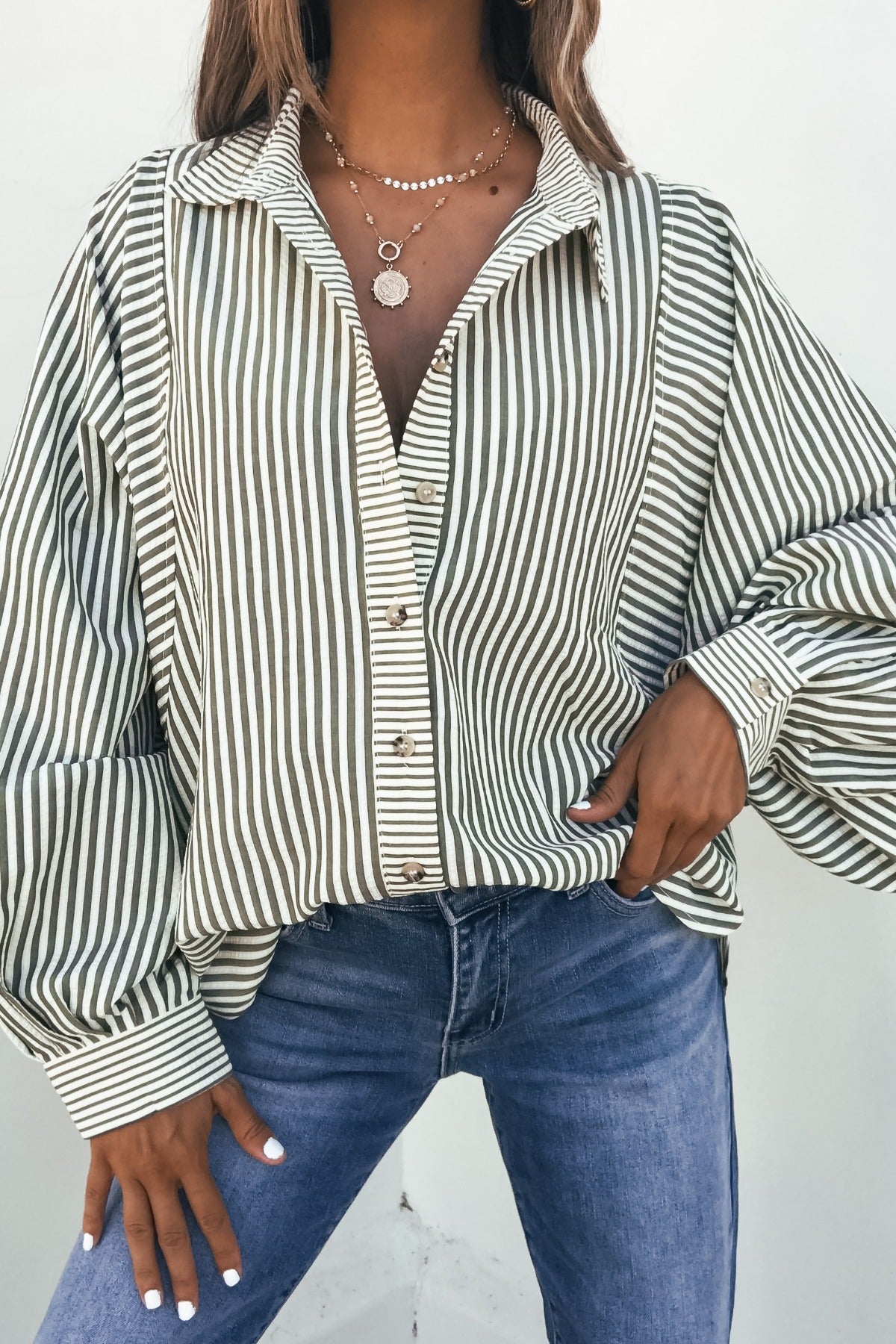 Woman in the Loose Ends Striped Shirt - Olive with blue jeans and layered necklaces.