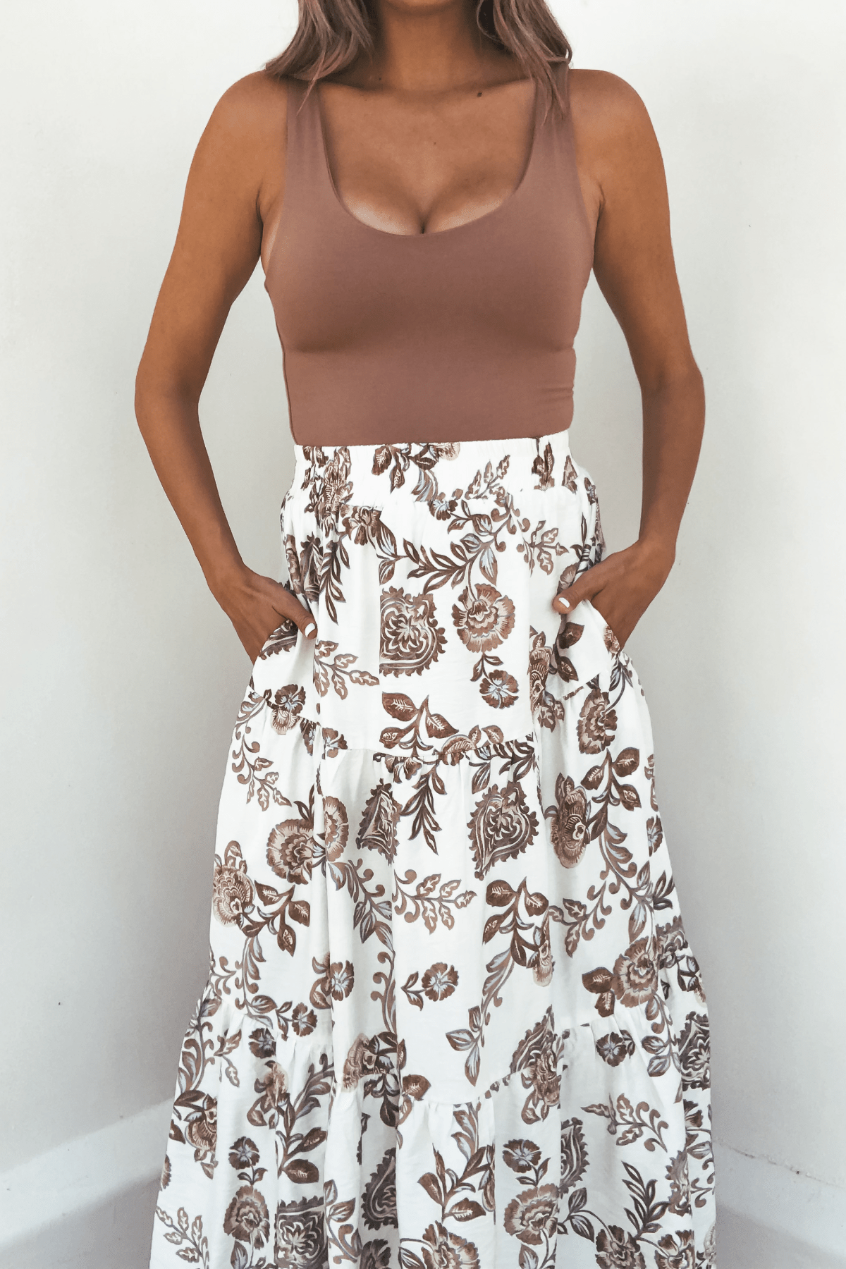 Model wears Lorelei Brown Floral Print Midi Skirt with a sleeveless top, standing against a white background.