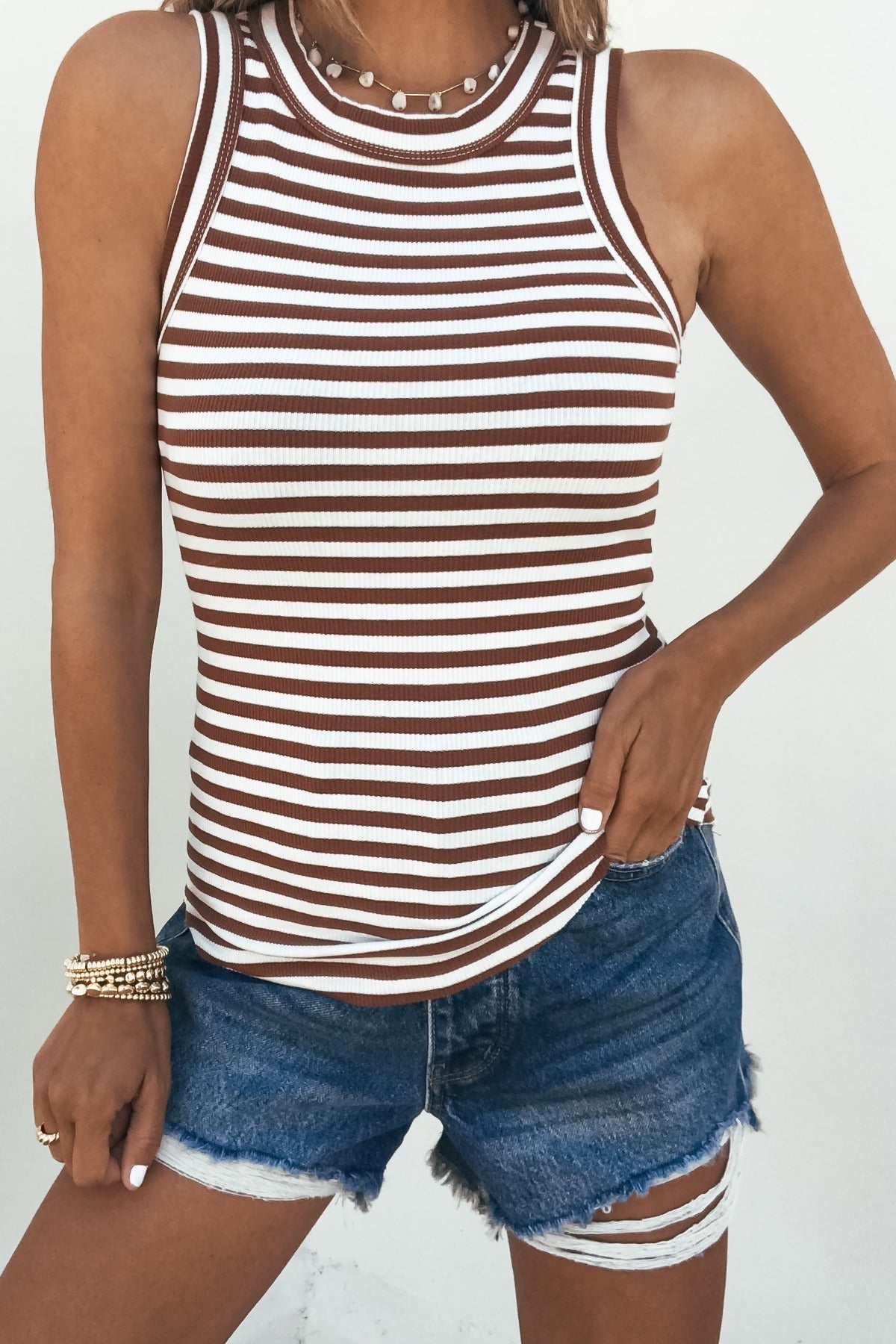 Woman wearing a Lorna Stripe Racerback Tank Top - Brick with frayed denim shorts, bracelets, and a necklace.