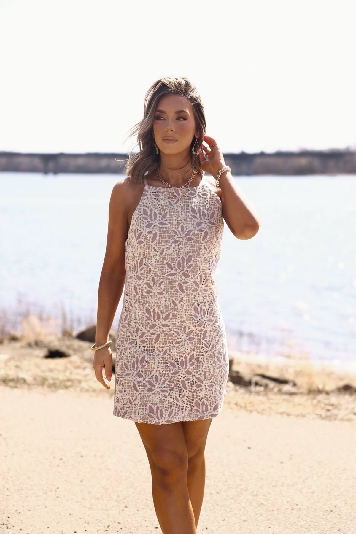 Woman in the Love & Lace Light Mauve Shift Mini Dress stands outdoors by the water on a sunny day.