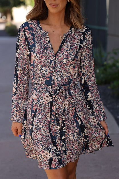 A woman in the Love Stitch Navy Floral Print Belted Mini Dress - FINAL SALE, enjoying a walk outdoors.