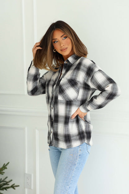 Woman wearing the Madelyn Charcoal Plaid Flannel Shirt and light blue jeans, posing with hand in hair against a white background.
