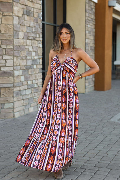 Smiling woman stands outside in the Maple Moments Halter Maxi Dress - Multi - DOORBUSTER, holding her colorful V-neckline dress.
