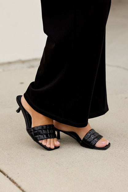 Wearing black pants and Matisse Rosanna Kitten Heels—black slip-on, square open toe—standing on a light sidewalk.