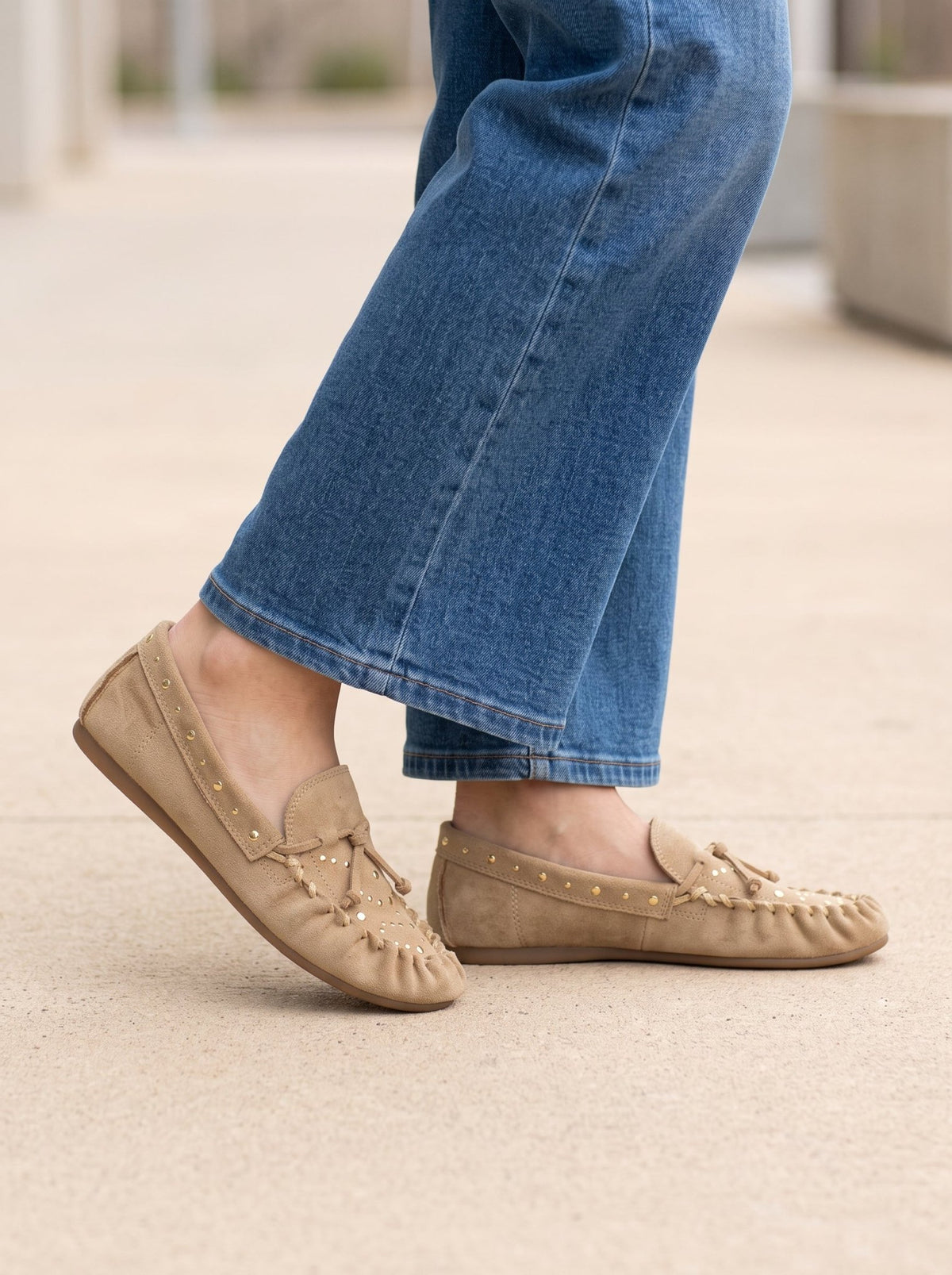 MATISSE SEBASTIAN NATURAL SLIP ON MOCCASINS in tan suede with gold studs and tie detail, worn with blue jeans.
