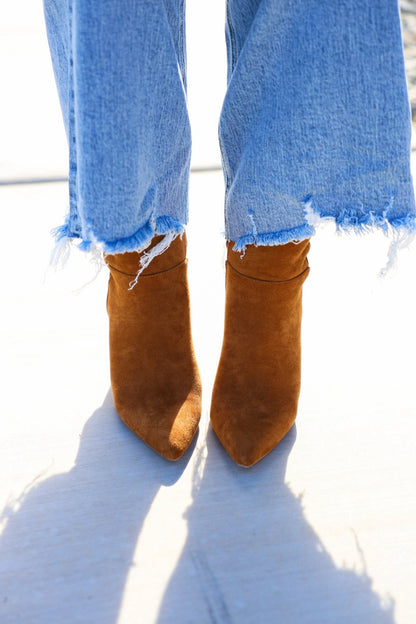 Person wearing frayed hem blue jeans and Matisse Spencer Camel Heeled Ankle Booties, standing on a light surface.