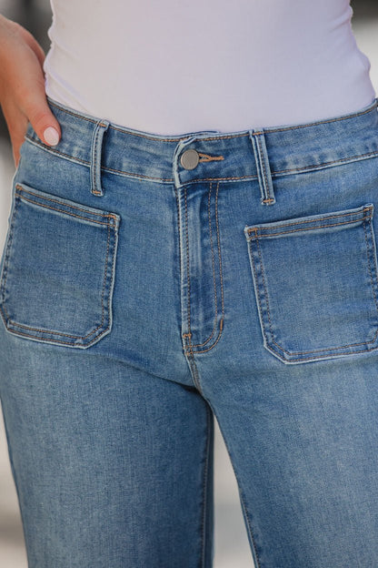 Close-up of a person wearing Medium Wash Patch Pocket Wide Leg Jeans and a white top, hand near the front pocket.