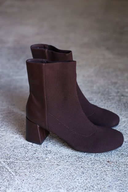 The MIA Bronwen Brown Heeled Ankle Booties with block heels and a modern silhouette, shown on a gray textured surface.