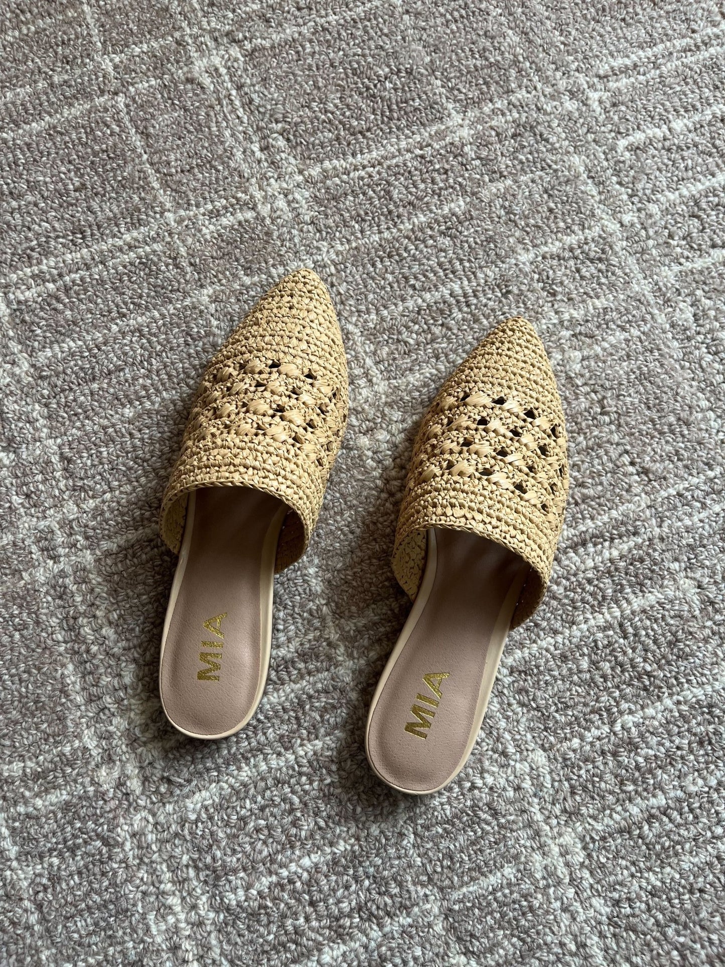 A pair of MIA Jany Natural Pointed Mules sits on a textured gray carpet.
