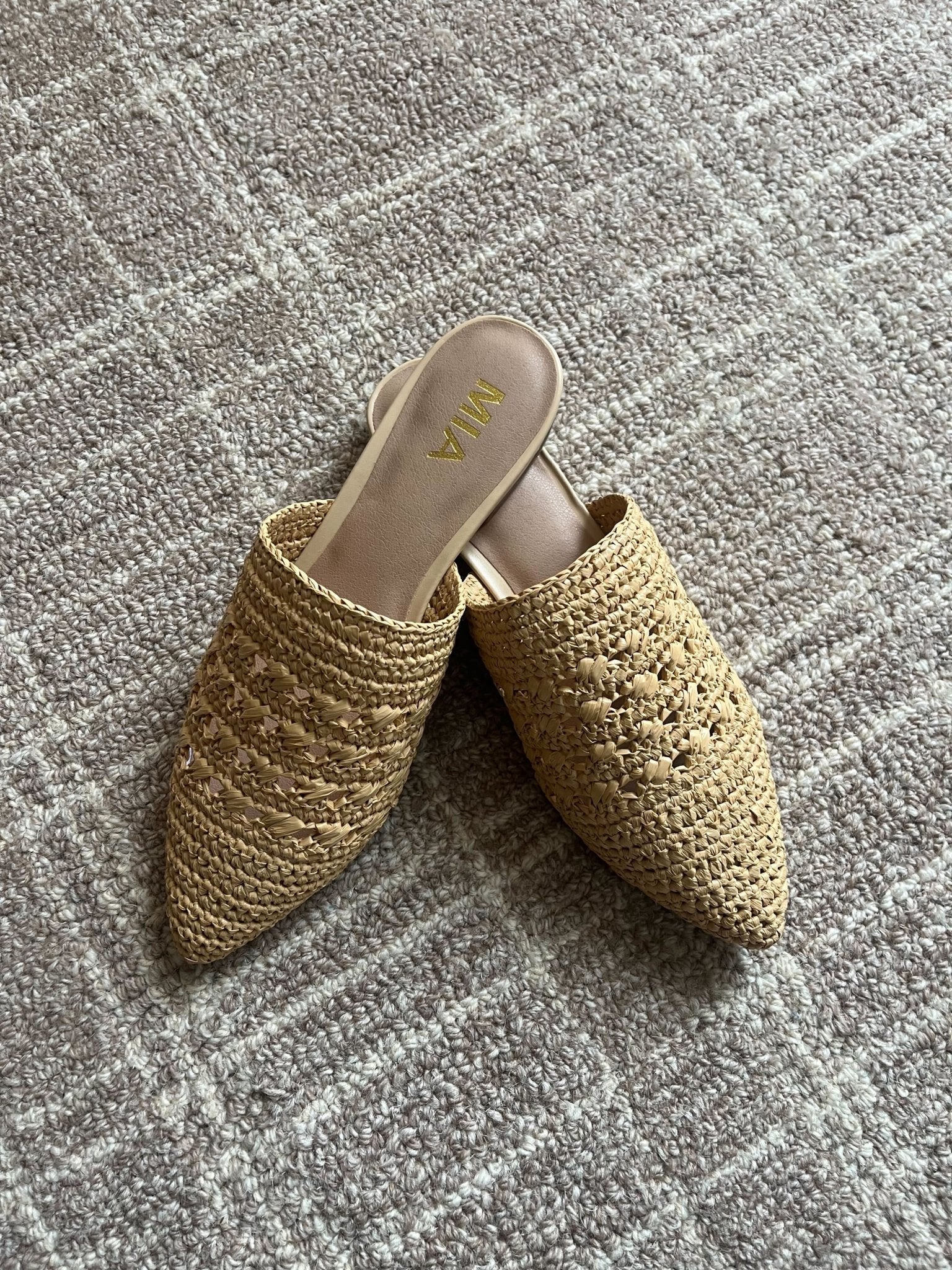 A pair of MIA Jany Natural Pointed Mules with a slip-on style sits on a textured, light-colored carpet.