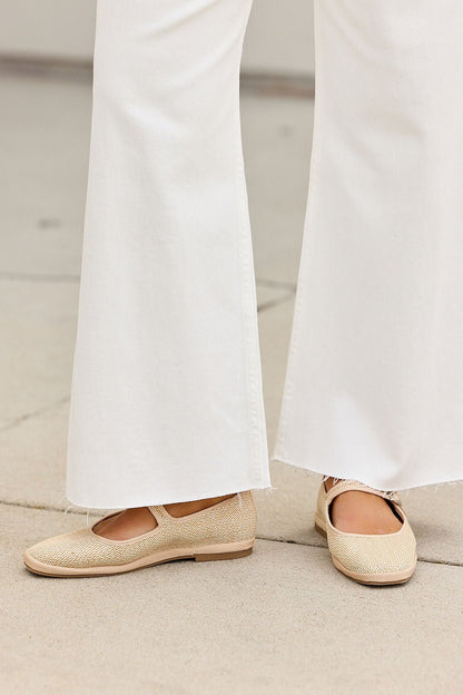 Person wearing MIA Monroe Ballet Flats in Natural with wide-leg white pants, standing on a light concrete surface.