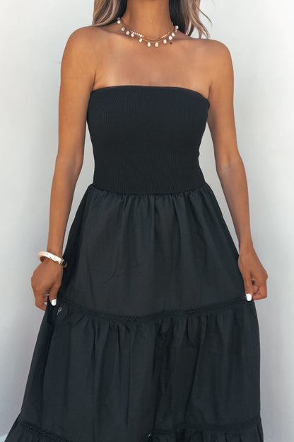 Woman in Midnight Ease Strapless Tiered Maxi Dress - Black with pearl jewelry, standing against a plain light background.